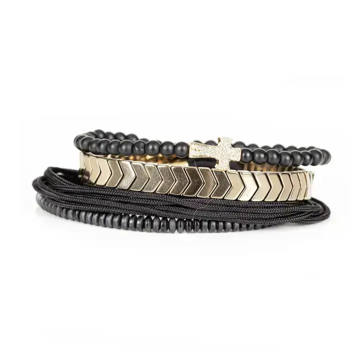 Black multi-layer men’s bracelet set with matte black beads, gold chevron metal bar, black cords, and cross accent detail on white background.