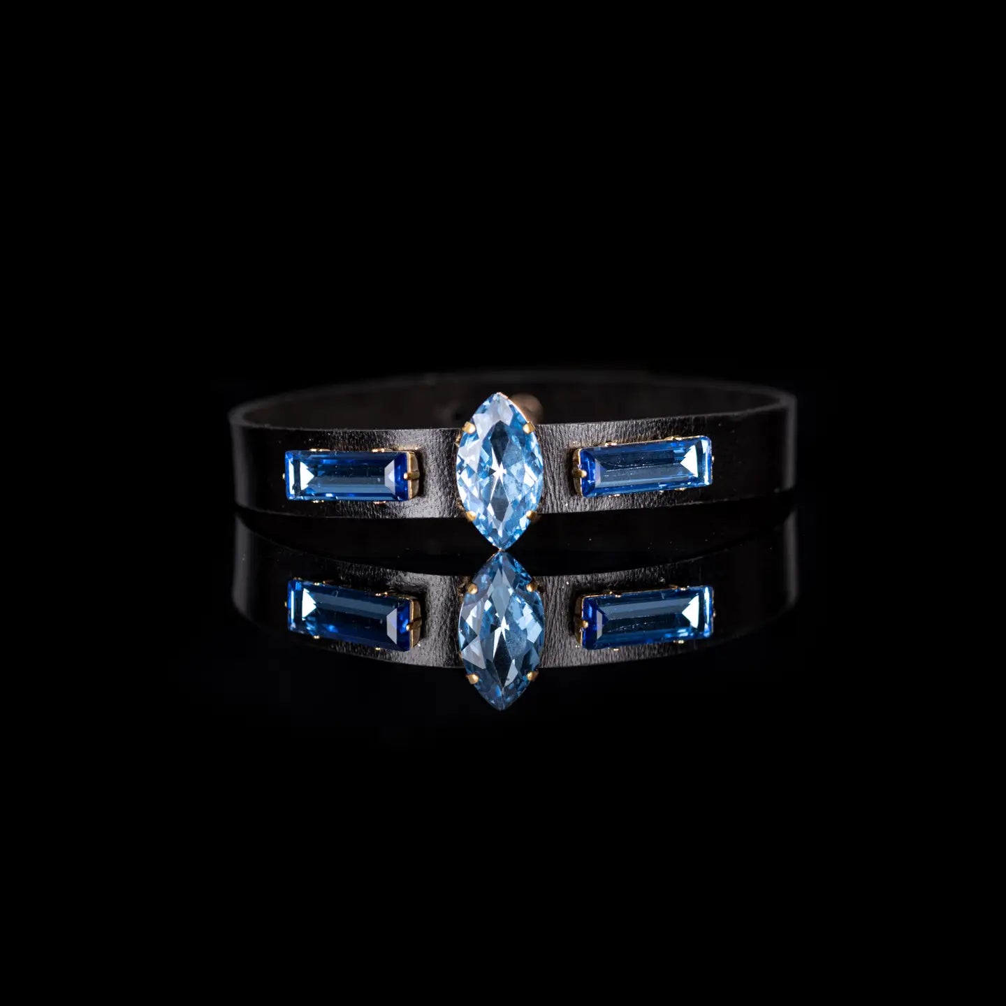 Black leather choker with a central marquise-cut blue crystal and two side baguette blue crystals, displayed on a white background.