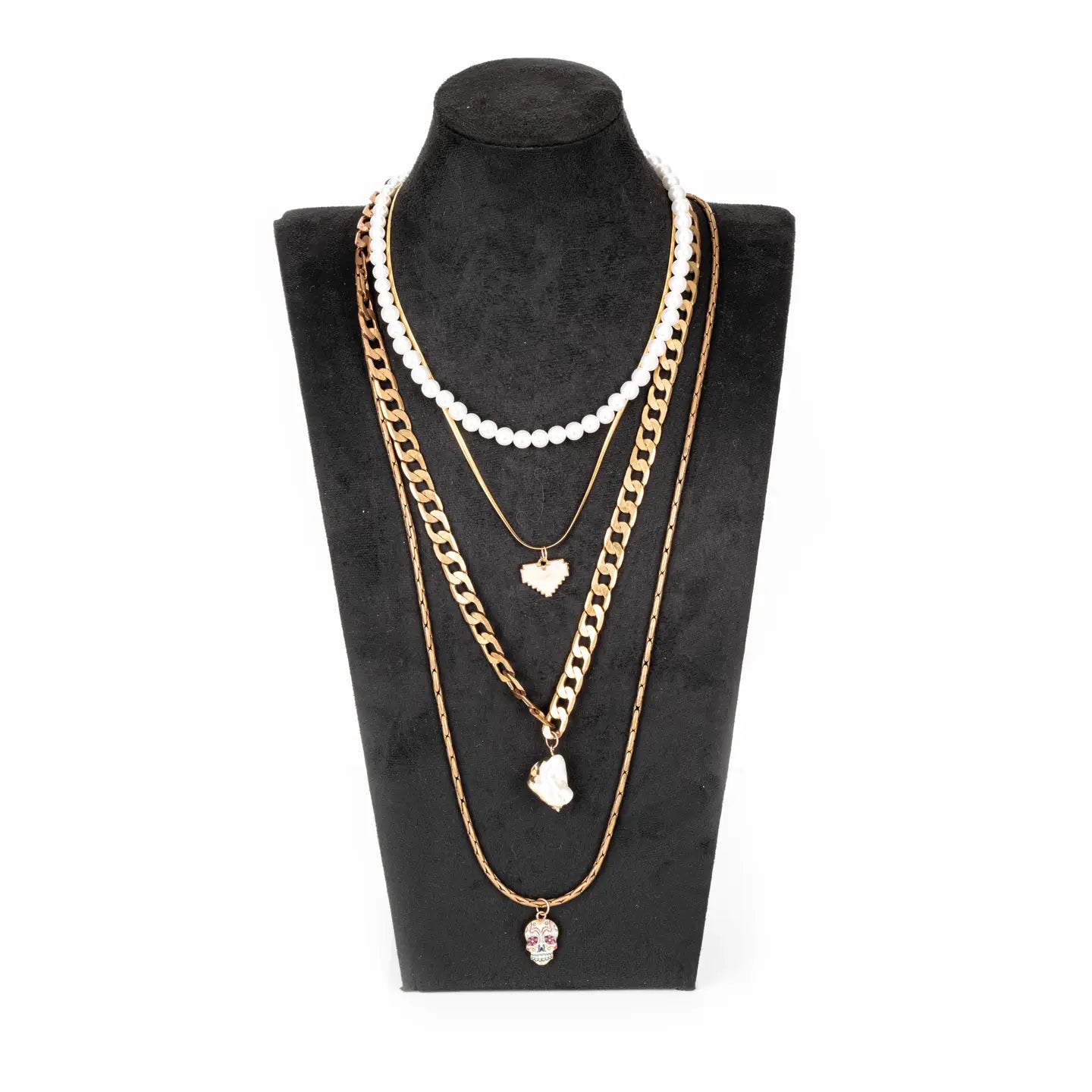 Layered gold necklace with white bead strand, heart charms, and skull pendant on white background.