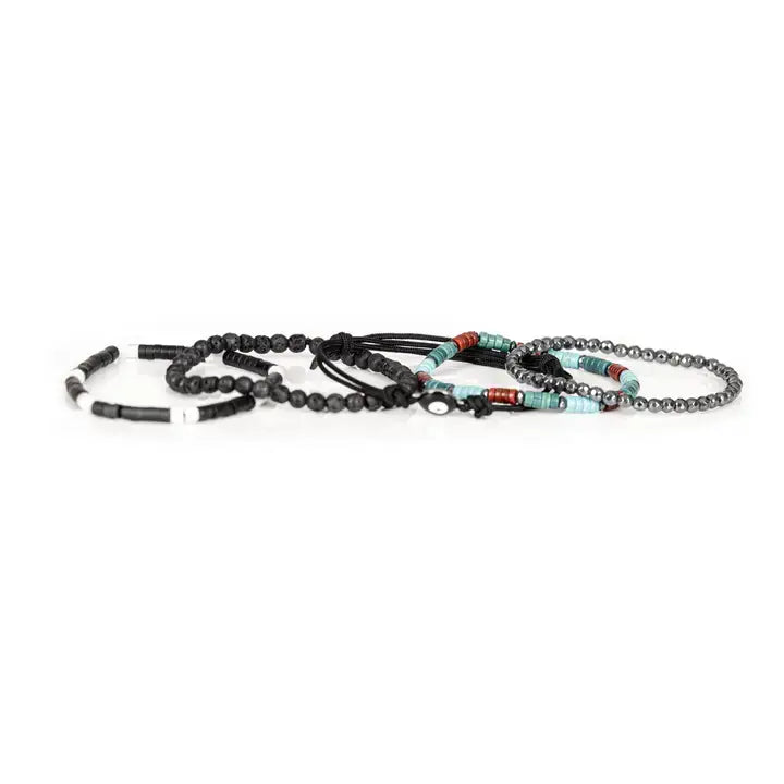 Men’s layered bracelet set featuring matte black lava stone beads, faceted hematite crystal beads, turquoise heishi beads, coral-red accent beads, black braided cord wraps, white and black spacer beads, and an evil eye centerpiece, stacked in a bold bohemian luxury design on a white background.