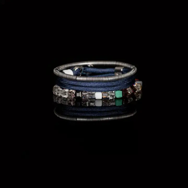 Men’s layered bracelet set featuring blue braided cord, silver-tone coil wrap, faceted crystal cube beads in blue, orange, gray, black, and clear tones, finished with polished metal accents in a modern luxury style on a white background.