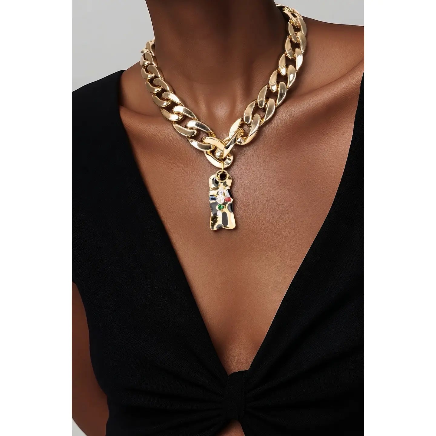 Gold chunky chain necklace with sculptural abstract pendant and subtle crystal accents on white background.
