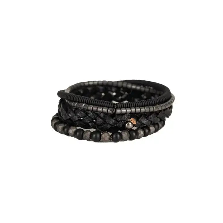 Black multi-layer men’s bracelet featuring braided leather, matte black onyx beads, faceted hematite stones, and layered metallic accents on a light background.