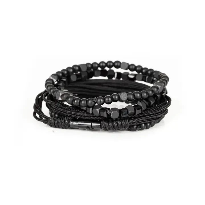 Black layered men’s bracelet set with matte black beads, faceted geometric crystal accents, cube beads, and braided rope wraps on white background
