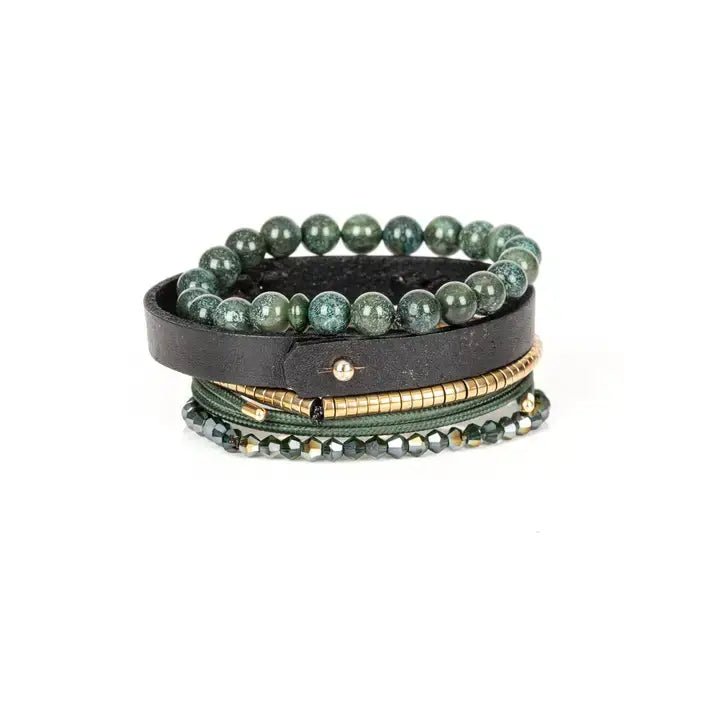 Men’s layered bracelet set featuring green natural stone beads, a black leather cuff with a gold-tone ID plate, olive braided cord wraps, gold-tone heishi beads, and faceted green crystal beads, stacked in a refined earthy luxury design on a white background.