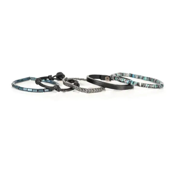 Blue and black multi-layer men’s bracelet set featuring silver chevron metal bar, blue-grey stone beads, black leather band, braided cord, and metallic hematite cube beads on a light background.