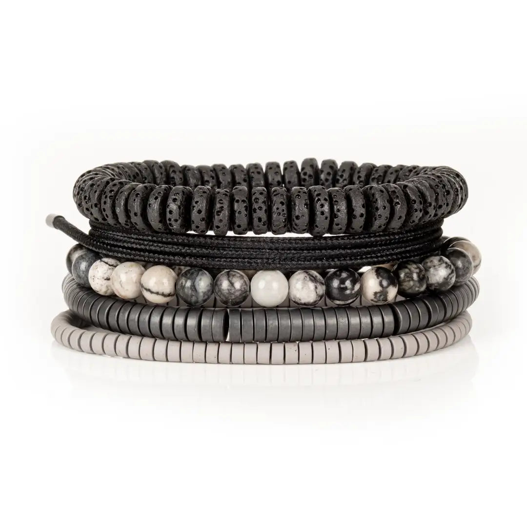 Men’s layered bracelet set featuring black lava stone disc beads, black braided cord wraps, white and gray marbled natural stone beads, black hematite coil beads, and light gray heishi beads, stacked in a sophisticated monochromatic luxury design on a white background.
