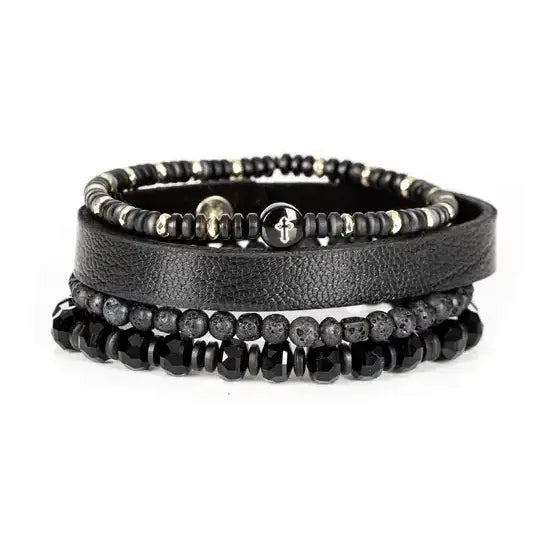 Men’s layered bracelet set featuring a black textured leather cuff, matte black lava stone beads, faceted black crystal beads, hematite accents, and a black beaded strand with a cross charm, stacked in a bold modern luxury design on a white background.