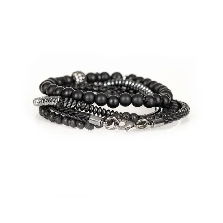 Black layered men’s bracelet set with lava stone beads, braided leather, hematite accents, matte black beads, and pavé centerpiece on white background.
