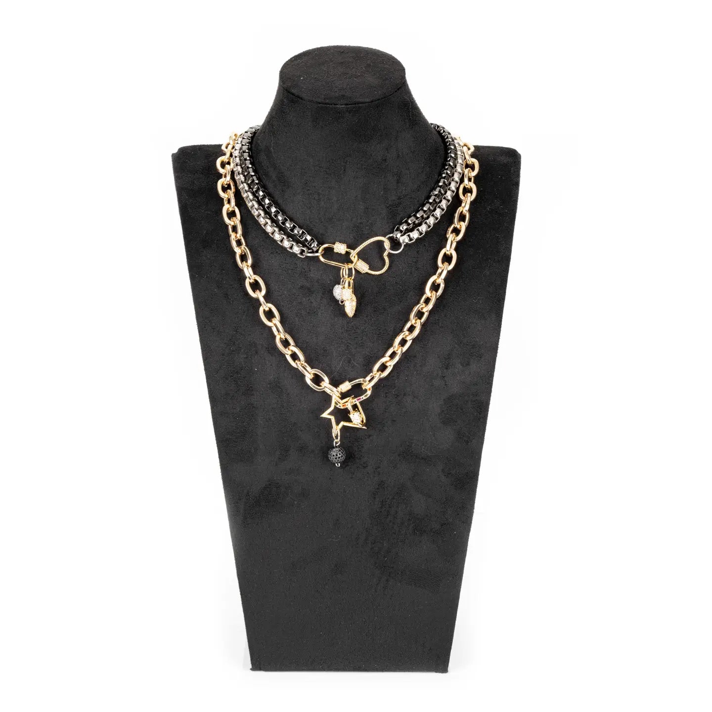 Mixed metal necklace with heart connector, charm details, and drop chain in gold and gunmetal tones on white background.