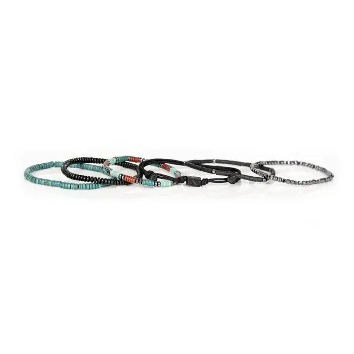 Black multi-layer men’s bracelet featuring hematite bead strands, braided rope layers, turquoise and red accent beads, geometric black centerpiece, and layered metallic details on a light background.