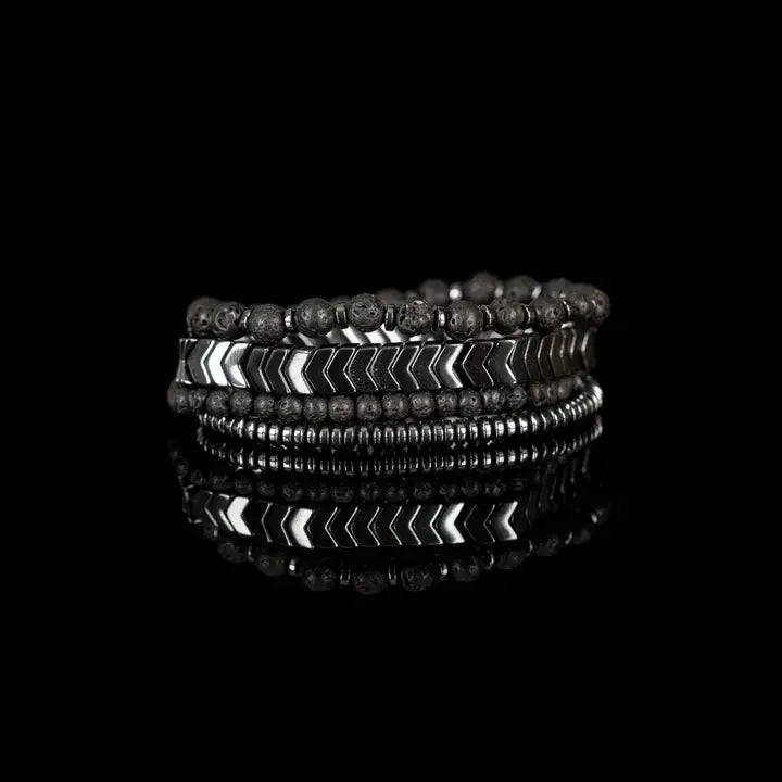 Black multi-layer men’s bracelet set featuring lava stone beads, silver chevron metal bar, hematite spacer beads, and layered metallic accents on a black background.