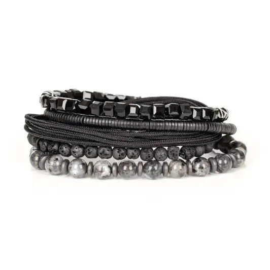 Men’s layered bracelet set featuring black faceted crystal beads, matte black lava stone beads, black braided cord, hematite spacer beads, and polished gray stone beads, stacked in a bold monochromatic luxury design on a white background.