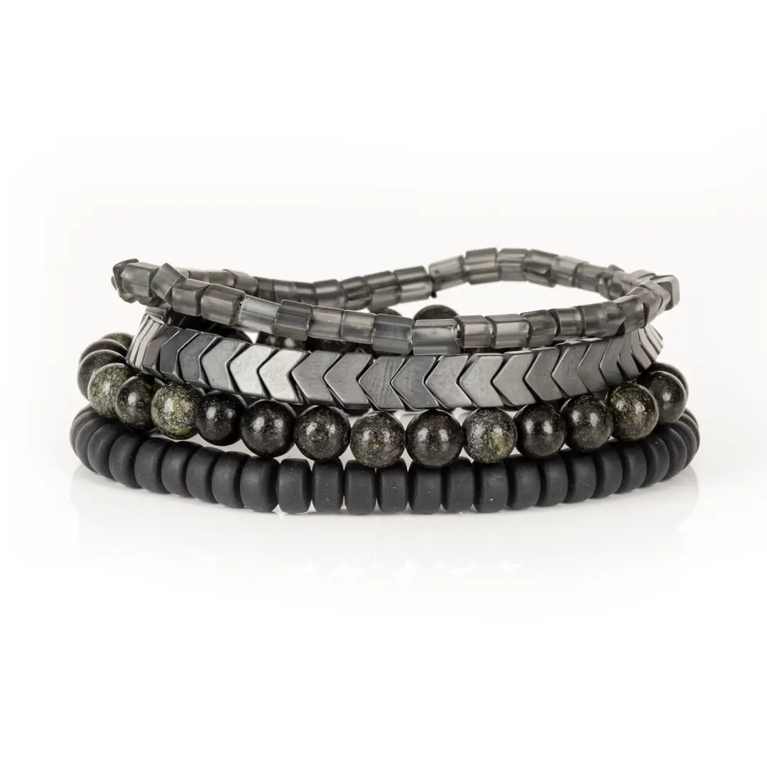 Men’s layered bracelet set featuring gunmetal chevron metal beads, smoky gray translucent beads, black matte heishi beads, and dark gray natural stone beads with subtle metallic shimmer, stacked in a sophisticated monochromatic luxury design on a white background.