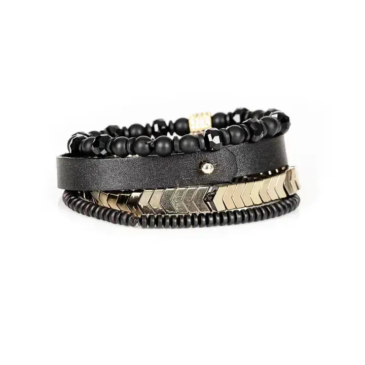 Black multi-layer men’s bracelet featuring faceted black onyx beads, black leather band, gold chevron metal bar, crystal cube accent, and layered metallic bead details on a light background.
