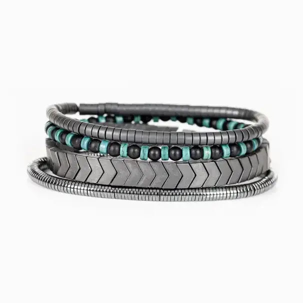 Men’s layered bracelet set featuring gunmetal chevron metal beads, black and turquoise beaded strands, dark hematite spacer beads, and silver-tone coil wrap accents, stacked in a modern industrial luxury design on a white background.