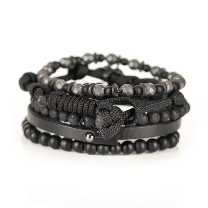 Black multi-layer men’s bracelet set featuring faceted hematite beads, matte black stones, lava stone accents, braided rope layers, and black leather strap detail on a light background.