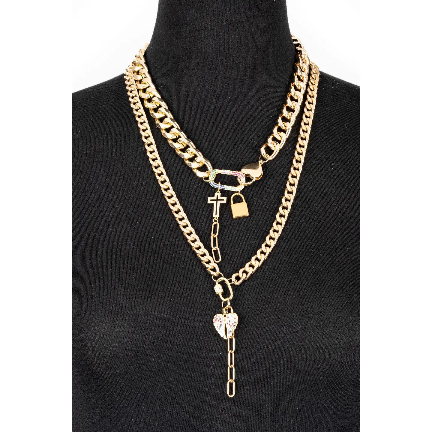 Layered gold chain necklace with cross, lock and heart charms on white background.