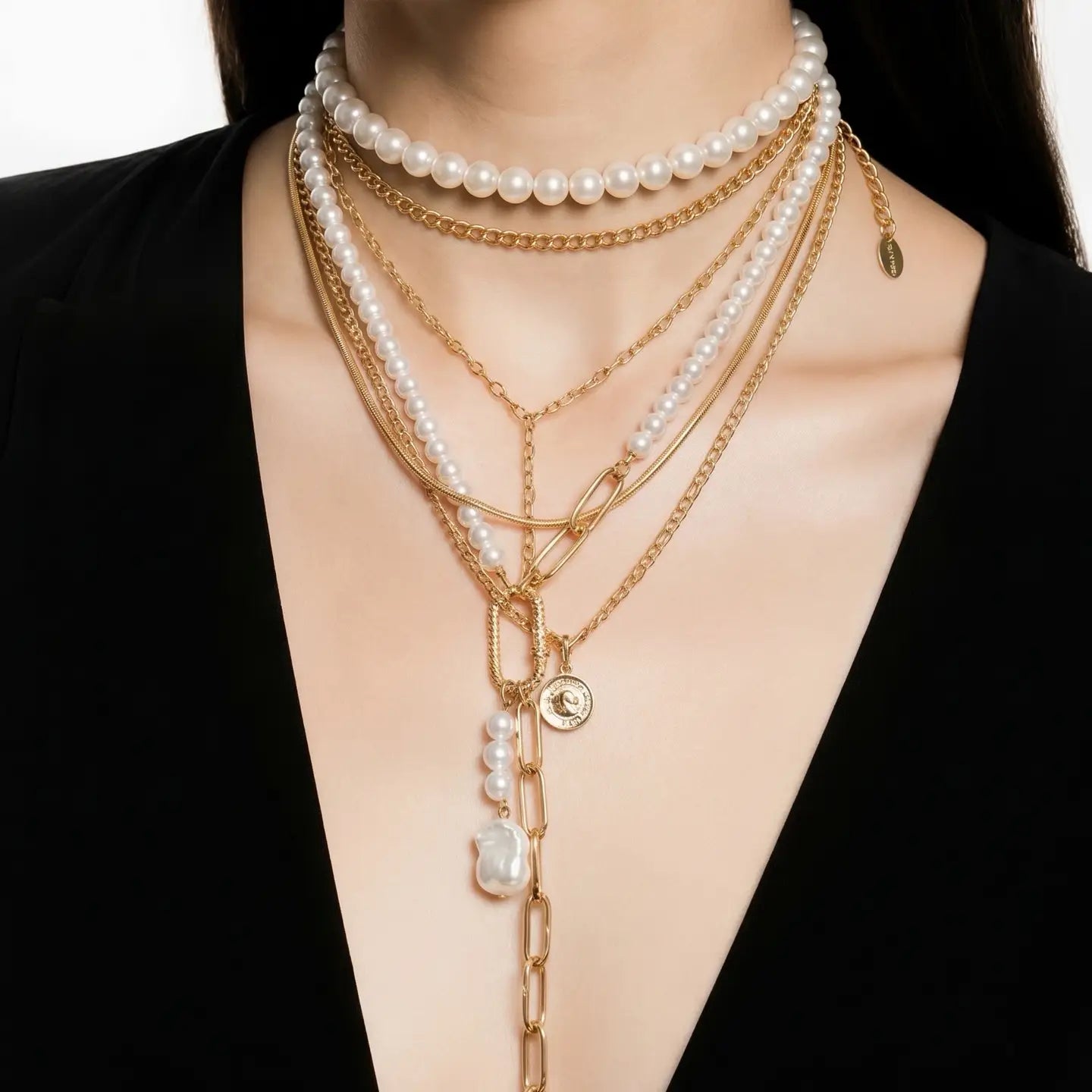 Layered pearl and gold chain necklace with drop chain detail on a white background.