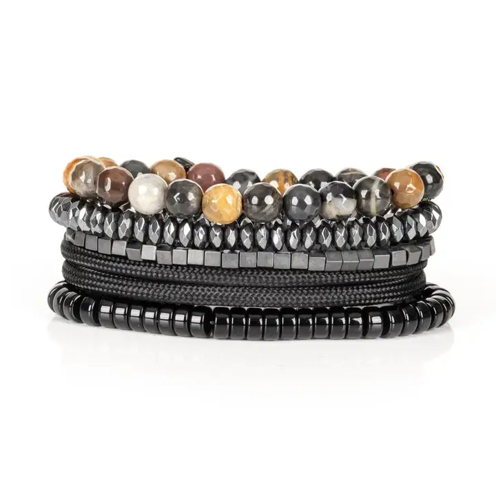 Black multi-layer men’s bracelet featuring natural multi-tone stone beads, faceted hematite strands, metallic cube accents, and braided black rope layers on a light background.