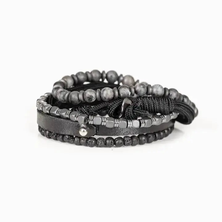 Men’s layered bracelet set featuring gray marbled natural stone beads, a black leather cuff, matte black lava stone beads, black braided cord, hematite cube beads, and metallic spacer accents, stacked in a sophisticated monochromatic luxury design on a white background.