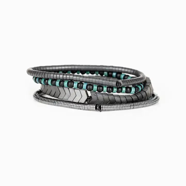 Men’s layered bracelet set featuring gunmetal chevron metal beads, black and turquoise beaded strands, dark hematite spacer beads, and silver-tone coil wrap accents, stacked in a modern industrial luxury design on a white background.