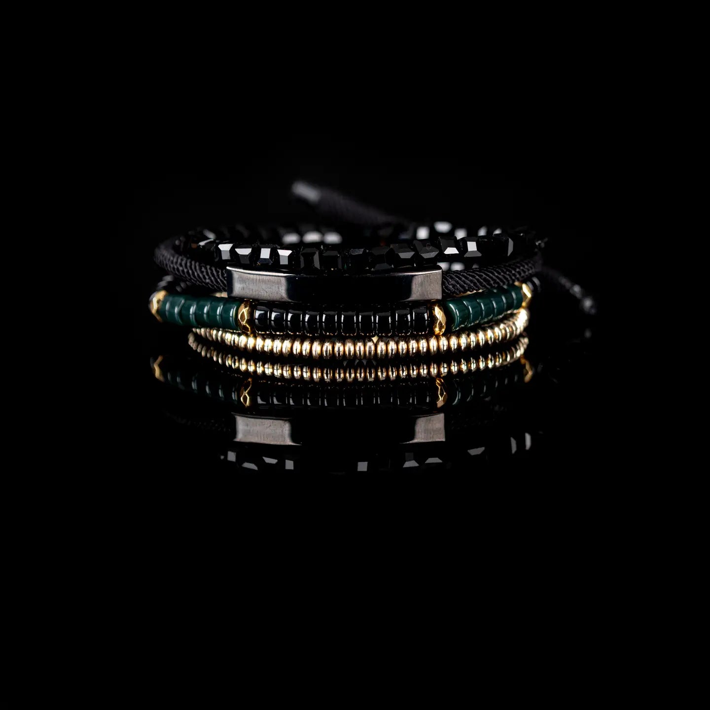 Men’s layered bracelet set featuring faceted black crystal beads, black braided cord wraps, a gunmetal ID bar centerpiece, black and deep green heishi beads, and gold-tone spacer beads, stacked in a sophisticated modern luxury design on a white background.