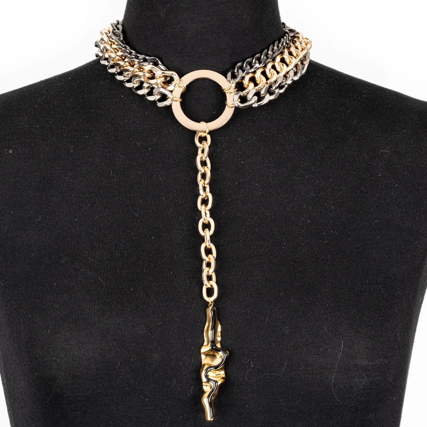Mixed metal chain necklace with central ring and long drop pendant in gold and gunmetal tones on white background.