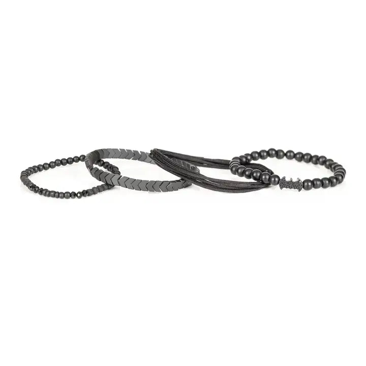 Black layered men’s bracelet set with matte black beads, Batman-inspired centerpiece, chevron metallic beads, crystal accents, and braided rope wraps on white background.