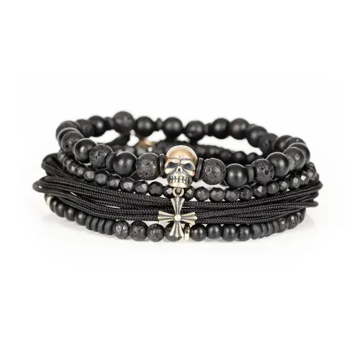 Black multi-layer men’s bracelet set featuring lava stone beads, matte onyx, faceted black stones, braided rope layers, metallic skull centerpiece, and cross accent on a light background.