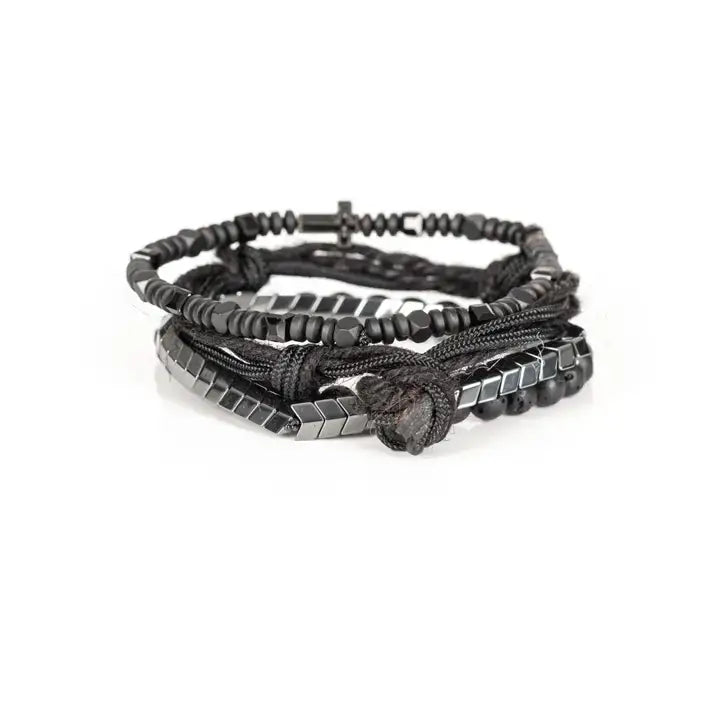 Black layered men’s bracelet set with lava stone beads, pavé cross detail, silver chevron metal strand, braided rope wraps, and woven texture accents on white background.