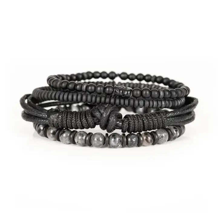 Black layered men’s bracelet set with matte black beads, braided rope wraps, and gray marbled stone accents on white background.