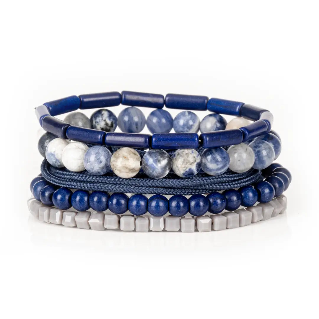 Men’s layered bracelet set featuring deep blue lapis-style beads, blue and white marbled natural stone beads, navy braided cord wraps, matte blue round beads, and light gray geometric heishi beads, stacked in a sophisticated nautical-inspired luxury design on a white background.