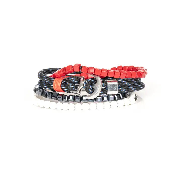 Men’s layered bracelet set featuring vibrant red cube beads, black braided cord with blue accents, faceted black hematite beads, and white heishi beads, stacked in a bold contemporary luxury design on a white background.