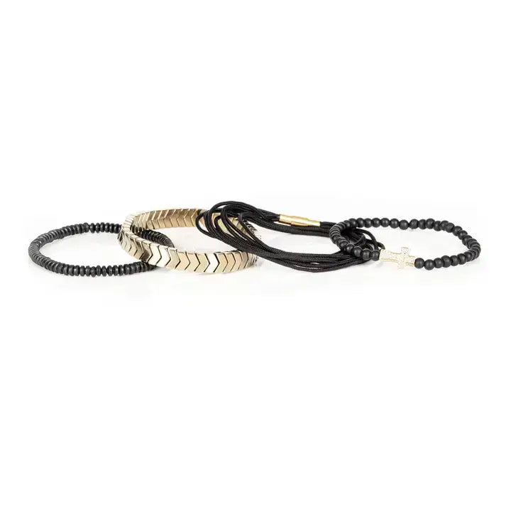 Black multi-layer men’s bracelet set featuring matte onyx beads, braided black rope, crystal cross centerpiece, gold chevron metal bar, and layered metallic accents on a light background.