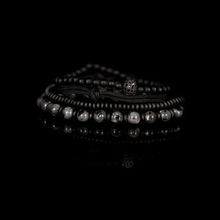 Black and gray layered men’s bracelet set with matte black beads, gray marbled stone accents, braided rope wraps, and pavé centerpiece on white background.