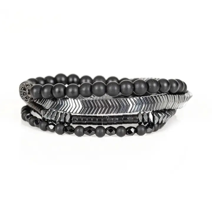 Black multi-layer men’s bracelet featuring matte black onyx beads, silver chevron metal bar, faceted black crystal beads, pyramid-cut hematite accents, and layered metallic details on a light background.