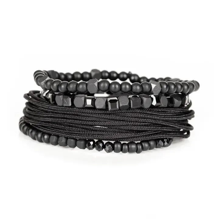 Black layered men’s bracelet set with matte black beads, faceted geometric crystal accents, cube beads, and braided rope wraps on white background