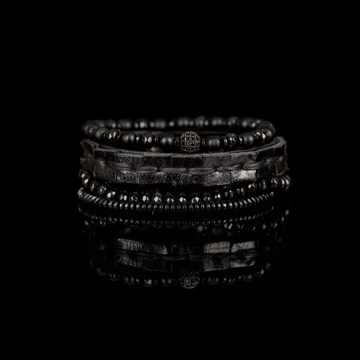 Black multi-layer men’s bracelet featuring woven leather band, matte onyx beads, faceted black crystal stones, crystal centerpiece accent, and hematite bead strand on a light background.