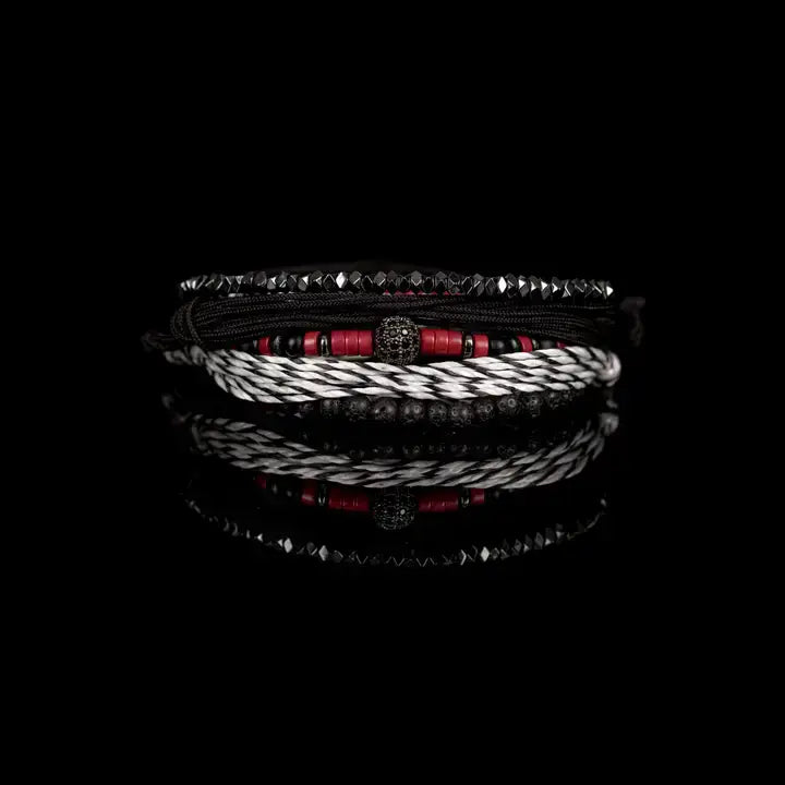 Black and red layered men’s bracelet set with lava stone beads, braided rope wraps, metallic accents, and pavé centerpiece on white background.
