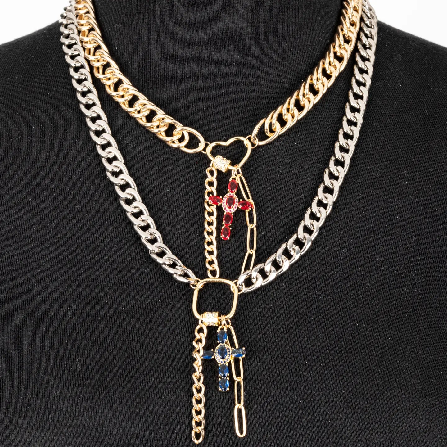 Mixed metal chain necklace with red and blue cross charms and layered drop chains on white background.