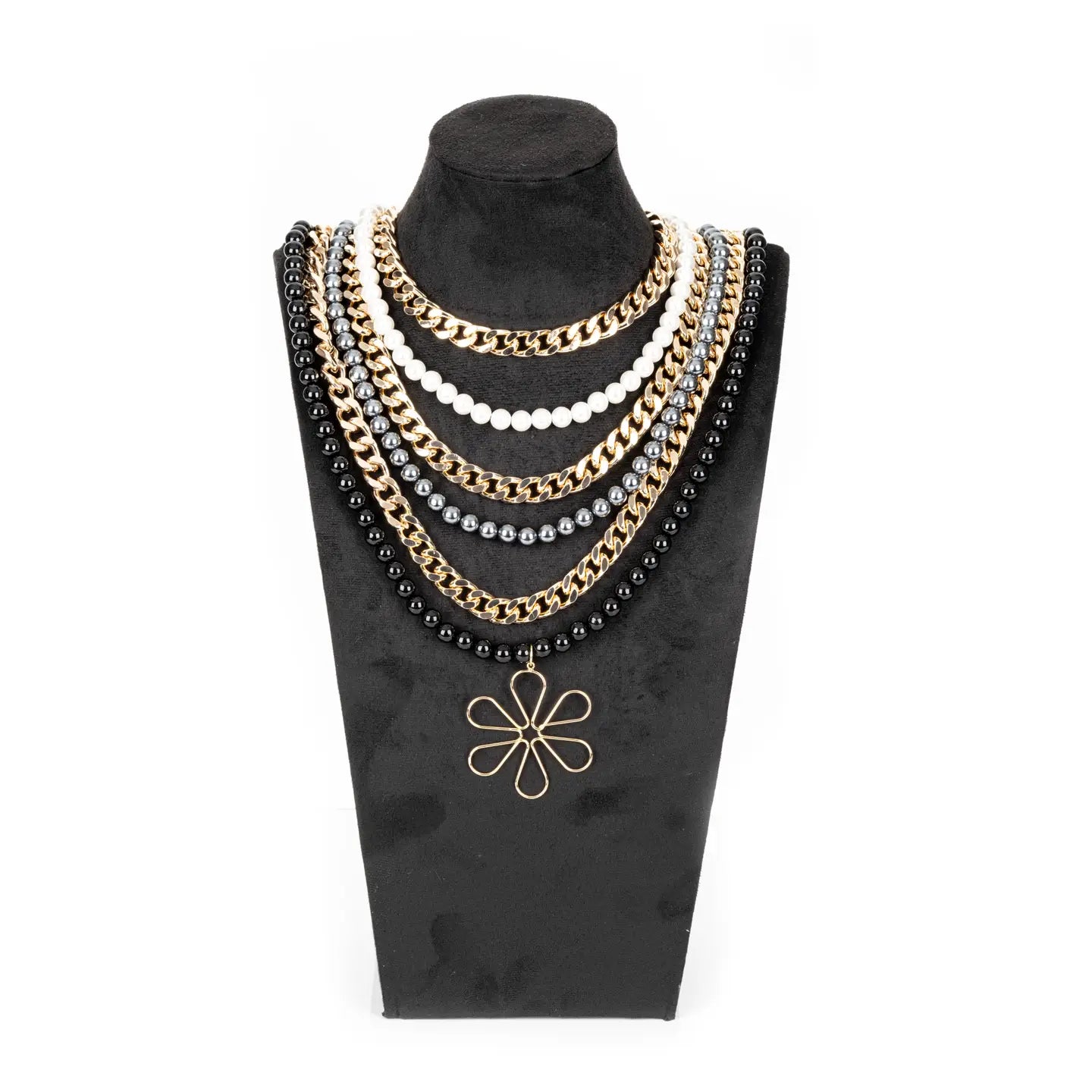 Multi-layer necklace with black, white, and metallic beads and chains, featuring a floral pendant, displayed on a white background.
