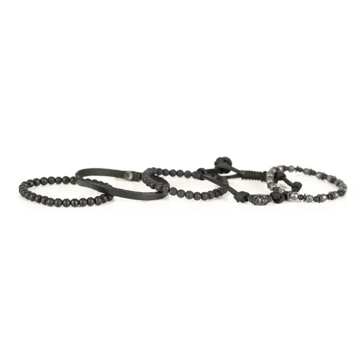 Black multi-layer men’s bracelet set featuring faceted hematite beads, matte black stones, lava stone accents, braided rope layers, and black leather strap detail on a light background.