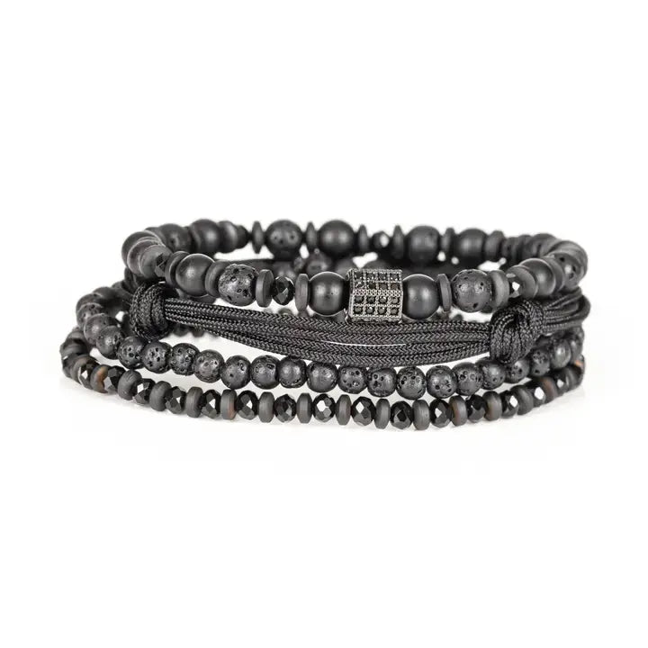 Black layered men’s bracelet set with lava stone beads, matte black beads, crystal accents, braided rope wraps, and pavé square centerpiece on white background.