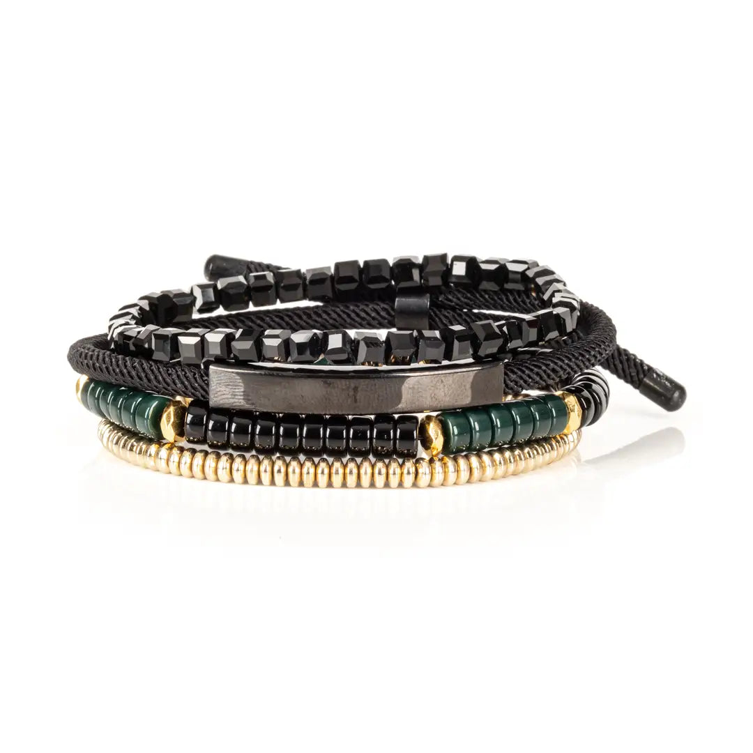 Men’s layered bracelet set featuring faceted black crystal beads, black braided cord wraps, a gunmetal ID bar centerpiece, black and deep green heishi beads, and gold-tone spacer beads, stacked in a sophisticated modern luxury design on a white background.