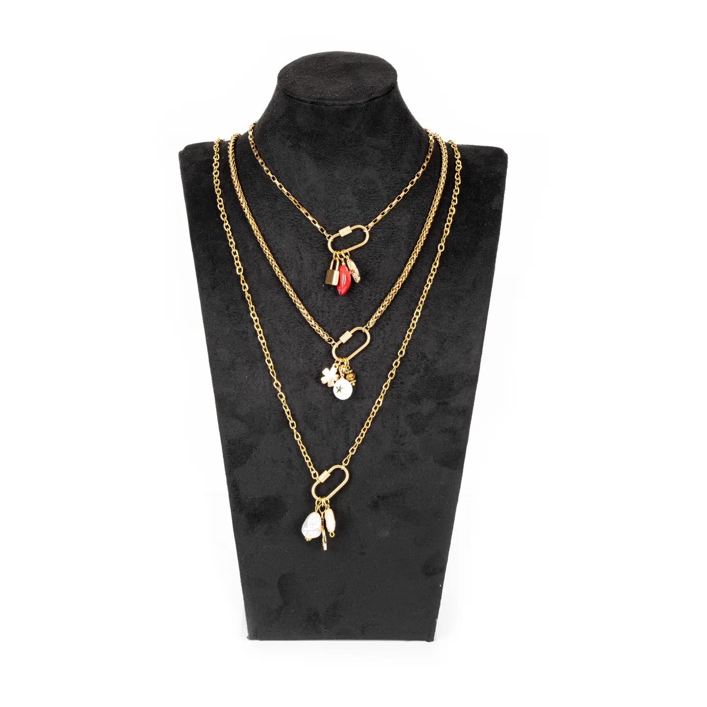 Layered gold necklace with three chains and small charm details on white background.