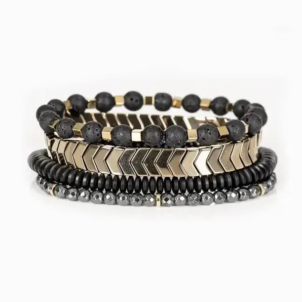 Men’s layered bracelet set featuring gold-tone chevron metal beads, matte black lava stone beads with gold-tone spacers, black heishi beads, and faceted hematite crystal beads, stacked in a sophisticated black and gold luxury design on a white background.