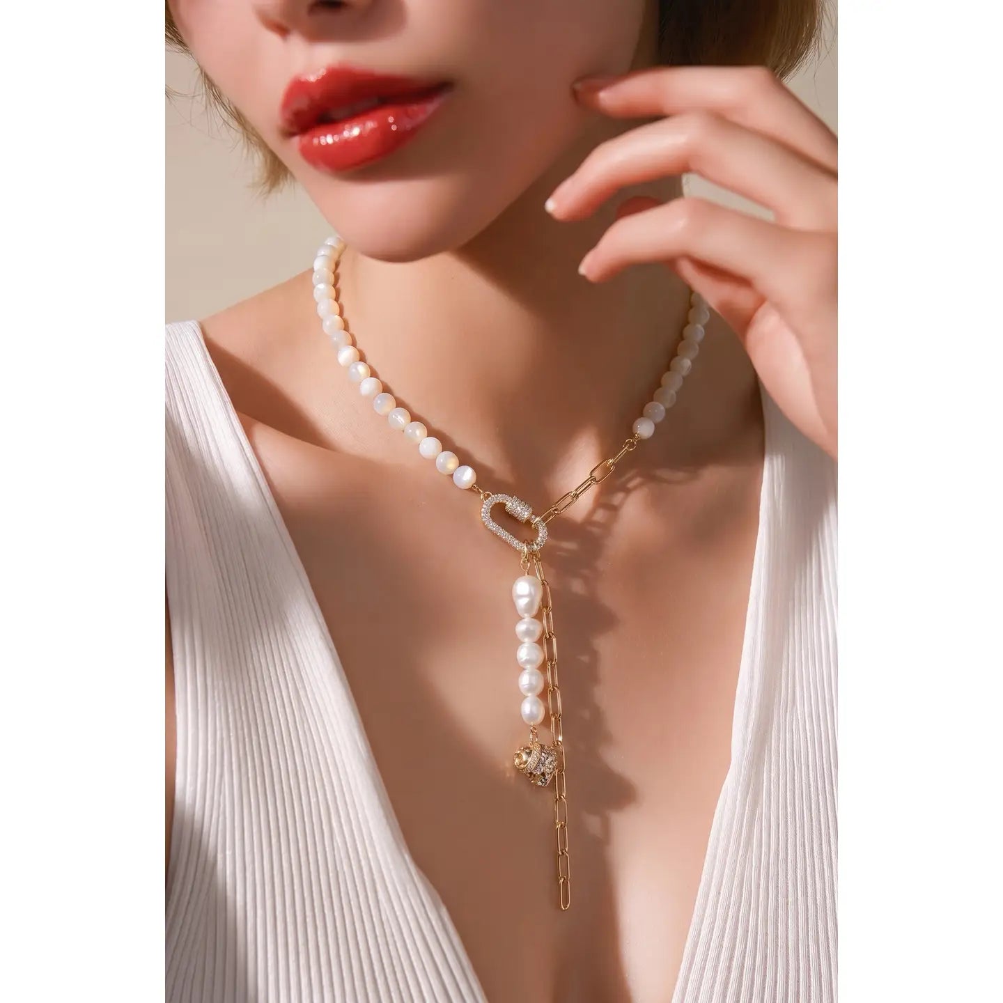 Pearl necklace with gold chain drop detail and crystal accent on white background.