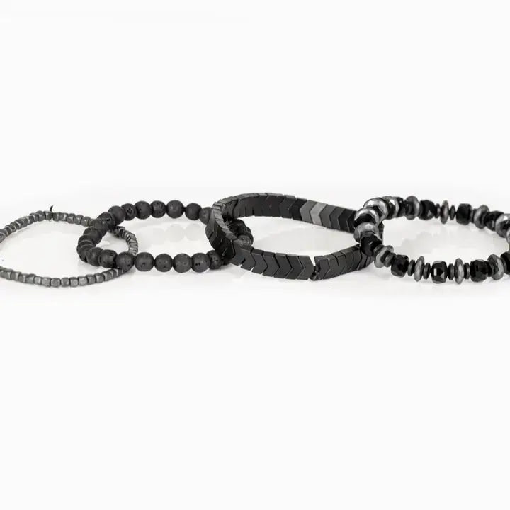 Men’s layered bracelet set featuring faceted black crystal beads, black and gray marbled stone beads, gunmetal chevron metal beads, matte black lava stone beads, and silver-tone hematite spacer beads, stacked in a bold monochromatic luxury design on a white background.