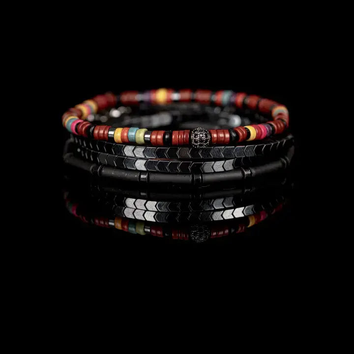 Multicolor multi-layer men’s bracelet featuring colorful disc beads, metallic hematite chevron strands, matte black tubular beads, and crystal centerpiece accent on a light background.